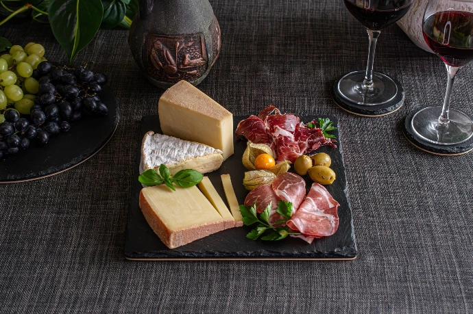 Quadratische Naturstein-Platte mit Holz-Unterseite. Exklusive Käseplatte für Charcuterie und Weinbegleitung im Shop.