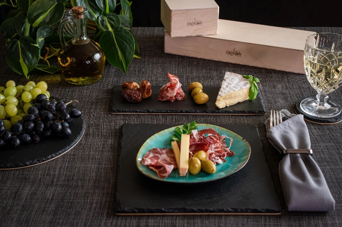 Edles Gourmet-Set aus Naturstein Boards mit Holzboden. Stilvoll mit Vorspeisen, Käse, Wein und Holzbox präsentiert.